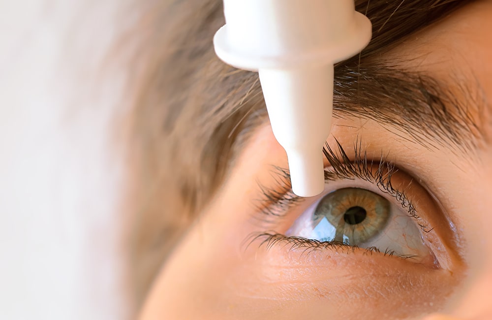 A close-up of a person applying cosmetic eye color changing drops, highlighting the start of a risky procedure.